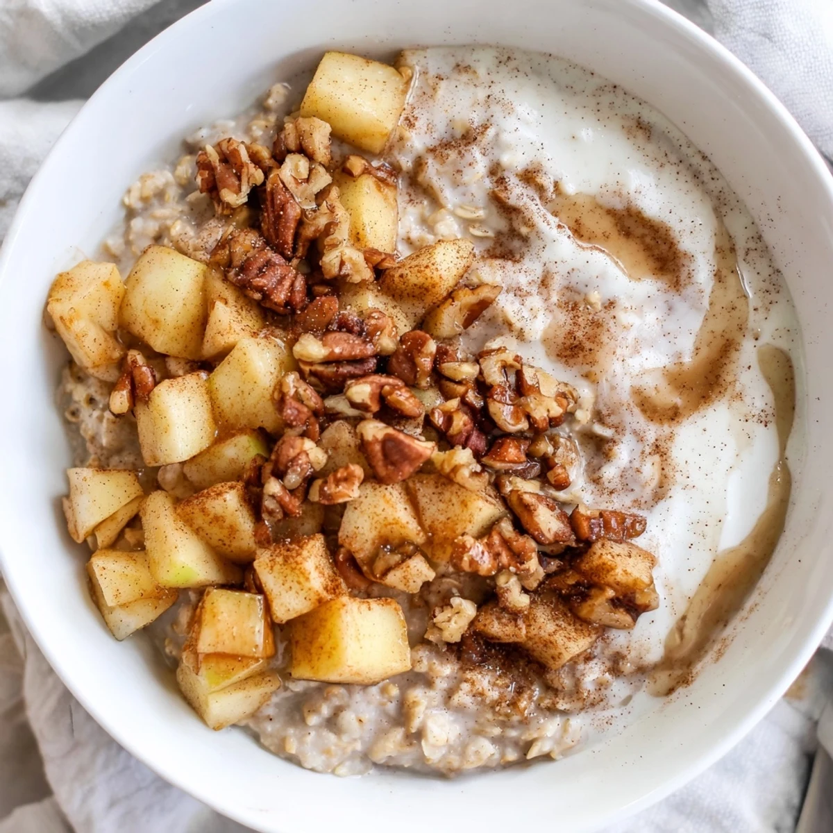 Warm and comforting apple pie oatmeal bowl topped with caramelized apples and toasted nuts.