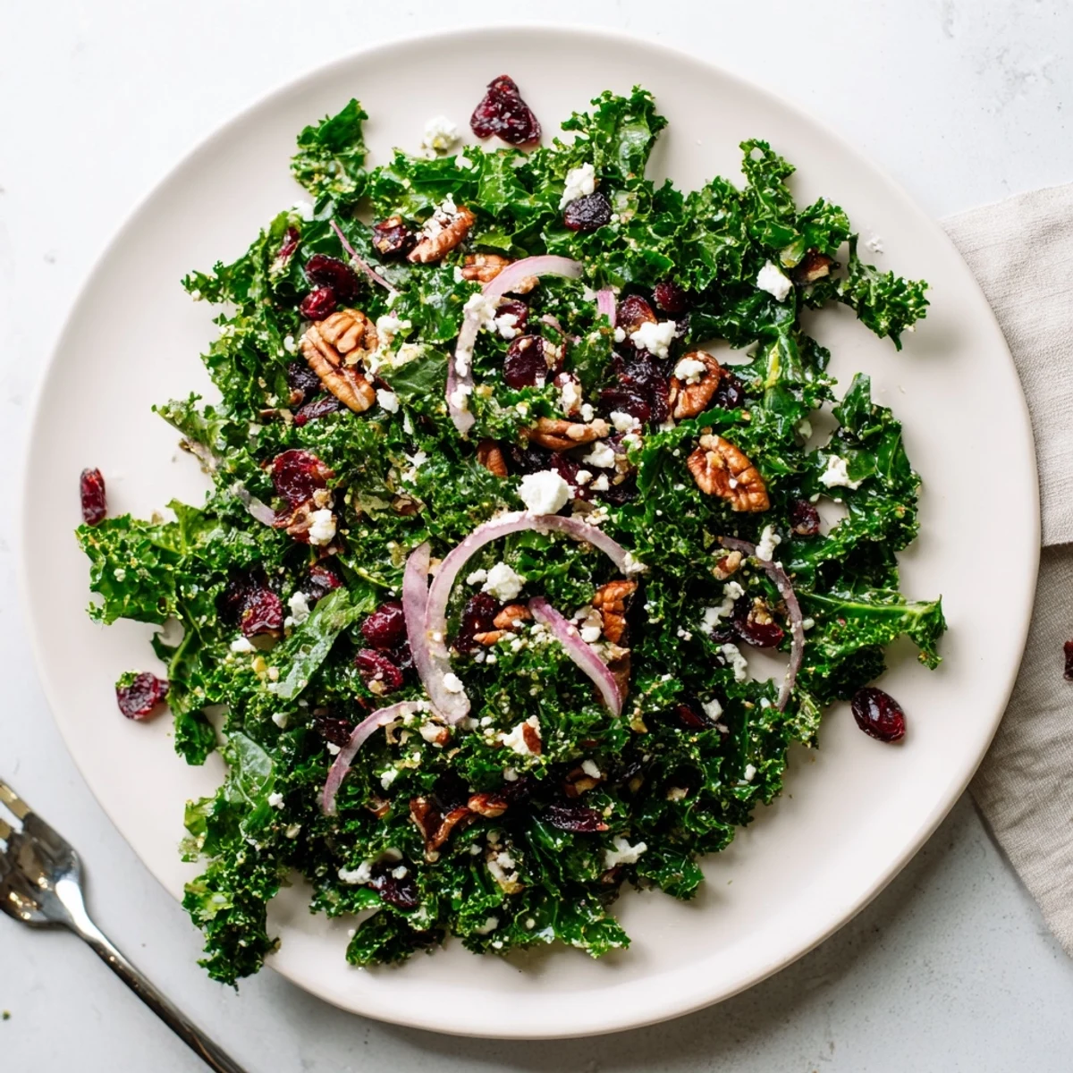 Warm kale salad with maple mustard dressing features massaged greens tossed with a sweet glaze, toasted pecans, and cranberries served in a rustic bowl.