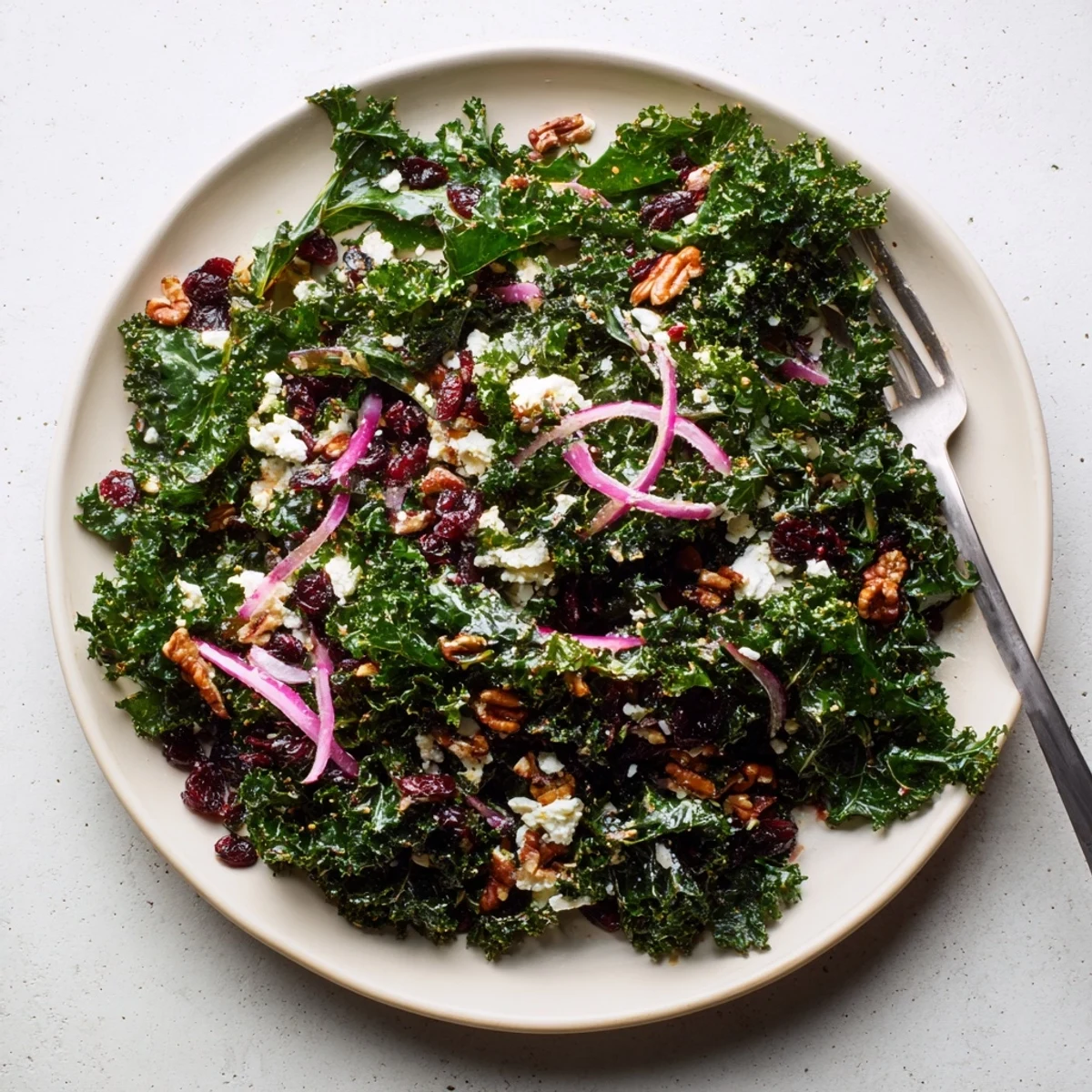 Vibrant kale salad with warm maple mustard dressing, topped with crunchy pecans, sweet cranberries, and crumbled feta for a comforting American side dish.