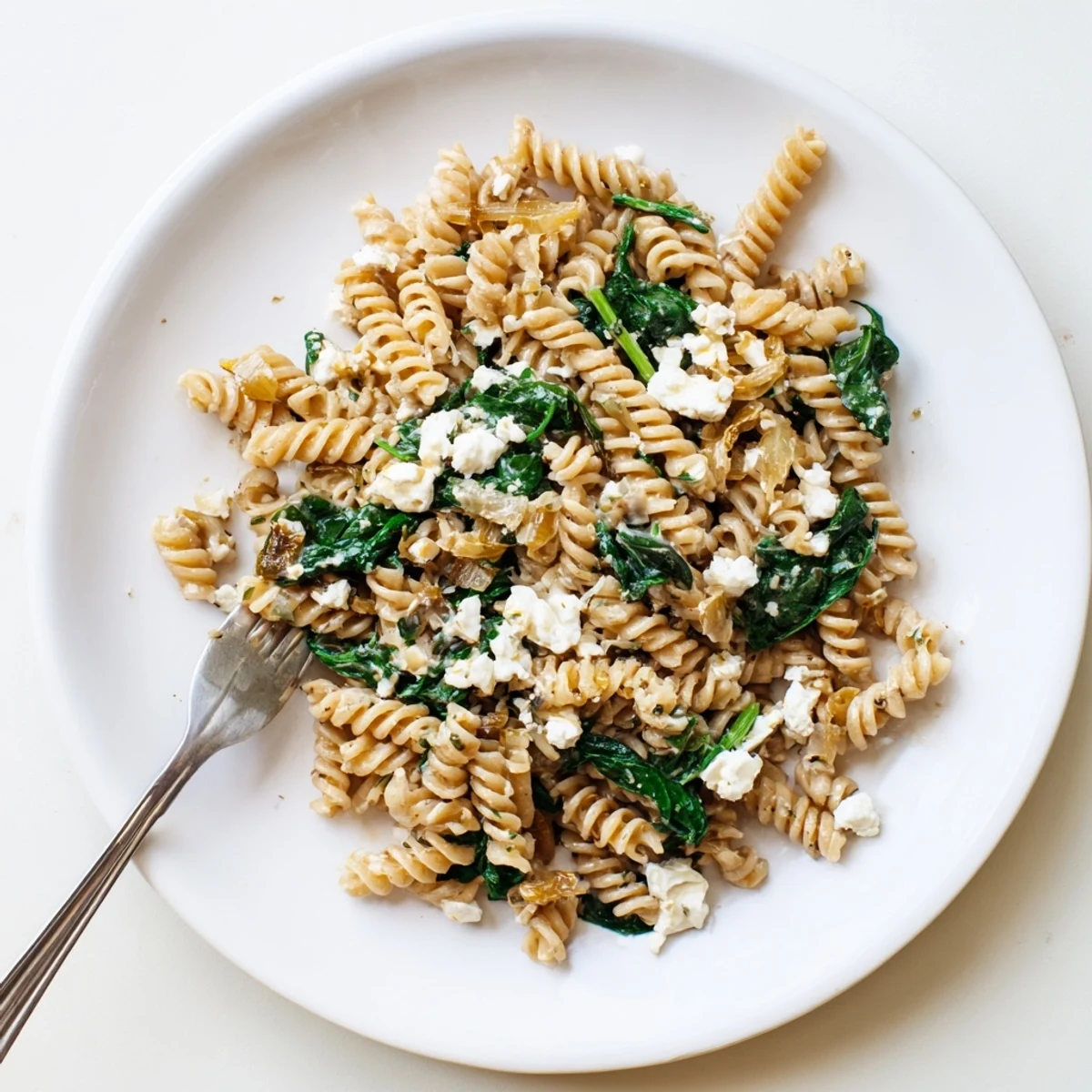 Steaming penne pasta tossed with crumbled feta and vibrant baby spinach in a creamy garlic sauce.  