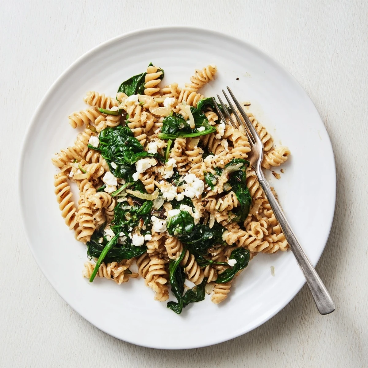A bowl of Creamy Feta Spinach Pasta with melted feta sauce clinging to al dente pasta and wilted spinach.