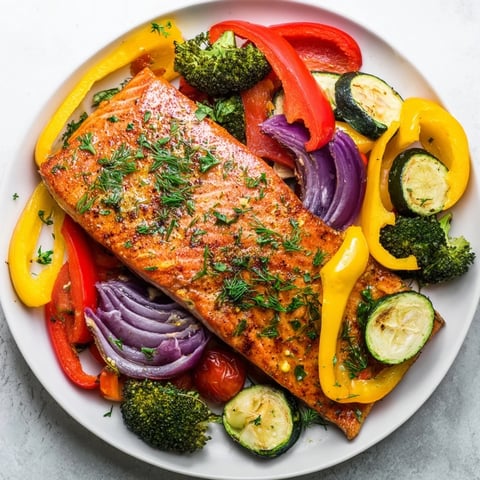 Flaky salmon sheet pan bake with colorful roasted vegetables, ready to serve with lemon wedges.