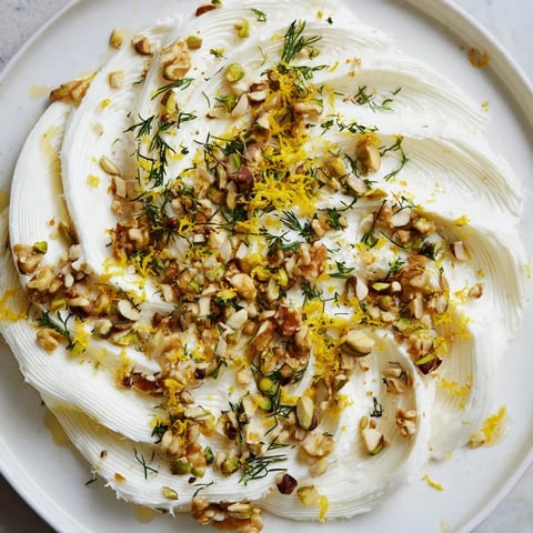 Creamy butter board charcuterie laden with toasted nuts and fresh herbs, ready to enjoy with a baguette.