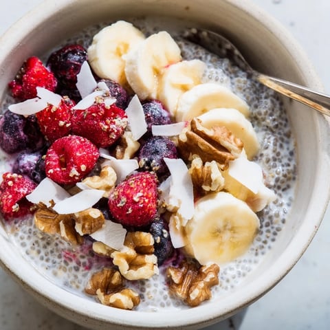 Creamy chia seed pudding layered in a glass, topped with fresh blueberries, sliced strawberries, and toasted coconut flakes for a vibrant breakfast treat.