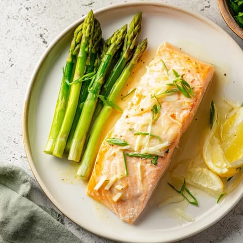 A close-up shot of the flaky Skillet Lemon-Butter Salmon, glistening with a bright lemon butter sauce.