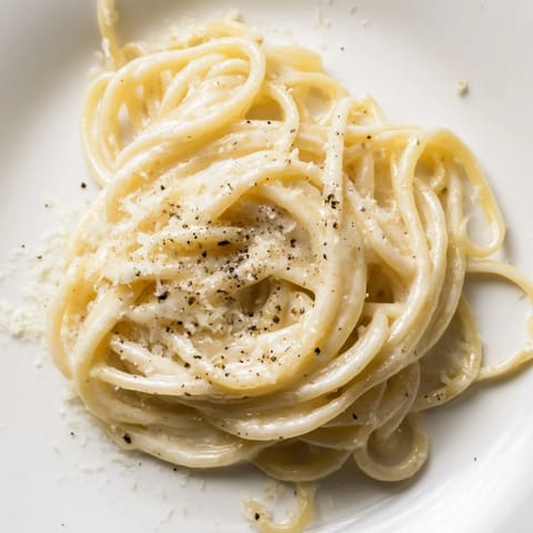 Close-up of creamy Lazy Girl Three-Ingredient Pasta, highlighting the Parmesan-coated pasta strands in the pot.