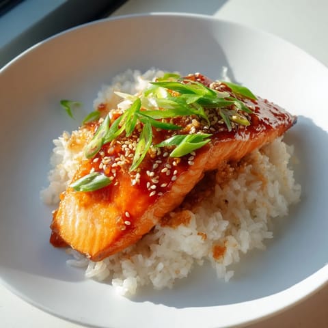A close-up of glistening sticky orange salmon, cooked to perfection, with a vibrant sauce.
