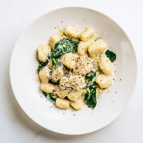 Golden-brown gnocchi pieces nestled in a velvety, aromatic Creamy Garlic Gnocchi sauce, topped with nutmeg and black pepper.  