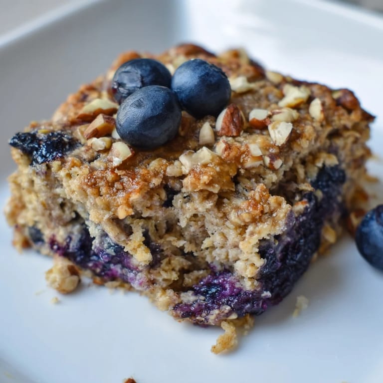 A close-up of delicious Blueberry Baked Oats, ready to eat with a swirl of vanilla yogurt.