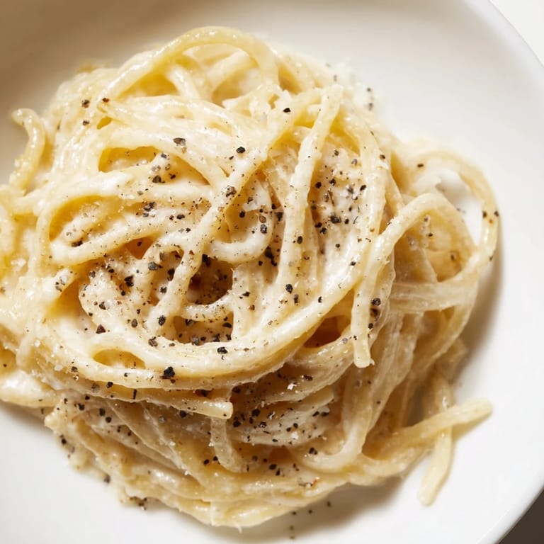 A plate of flavorful Lazy Girl Three-Ingredient Pasta, peppered with black pepper, ready to be enjoyed.