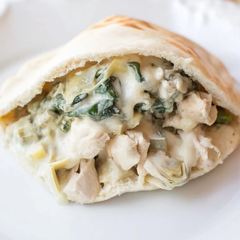 Freshly baked Spinach Artichoke Chicken Stuffed Pitas reveal a warm, savory filling of tender chicken, spinach, and artichokes.