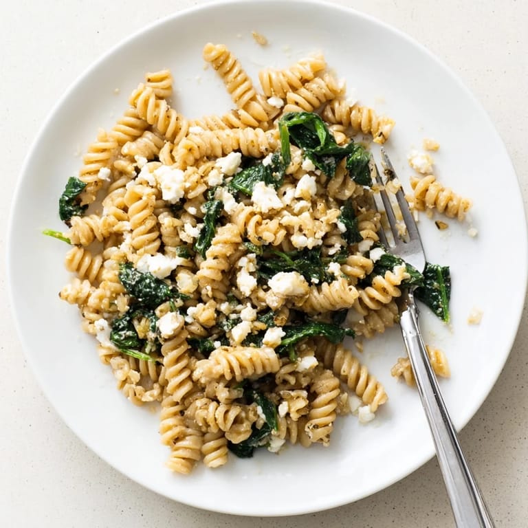 Creamy Feta Spinach Pasta garnished with fresh basil and lemon zest, served warm for a comforting meal.  