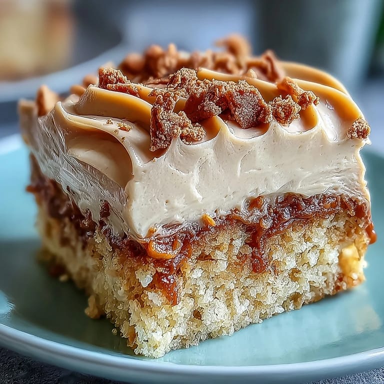 Decadent Baked Biscoff Cake with Creamy Lotus Frosting served on a white plate, ready to enjoy with a hot cup of coffee.