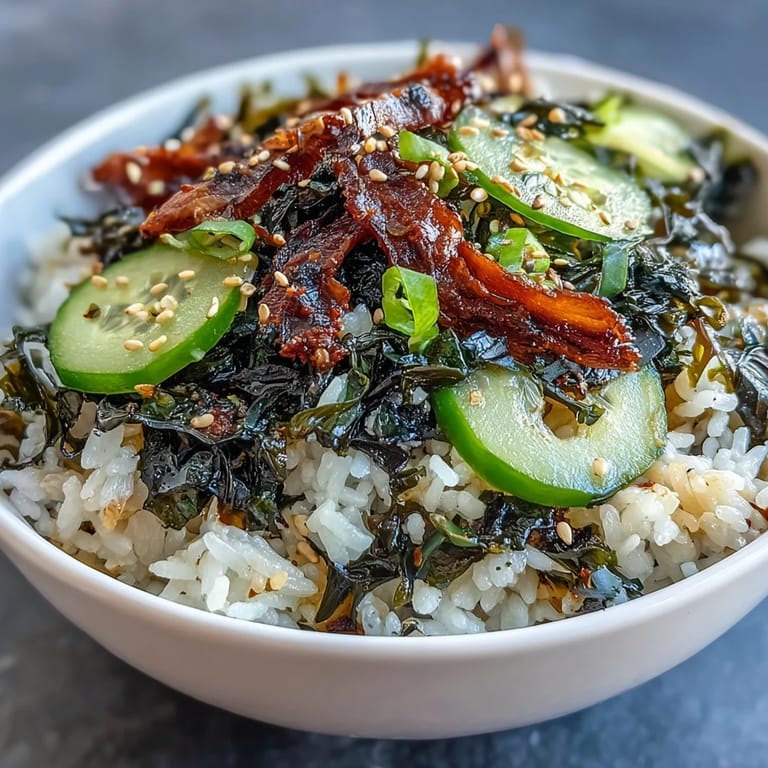 Nourishing Seaweed & Nori Rice Bowl featuring rehydrated wakame, nori strips, and fresh cucumber over fluffy sushi rice, garnished with sesame seeds.