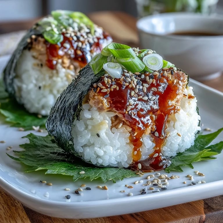Close-up of triangular onigiri with spicy tuna filling, glossy rice, and nori wrapping, ideal for sushi lovers on the go.